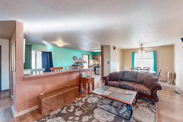 living area featuring ceiling fan, wood finished floors, visible vents, and baseboards