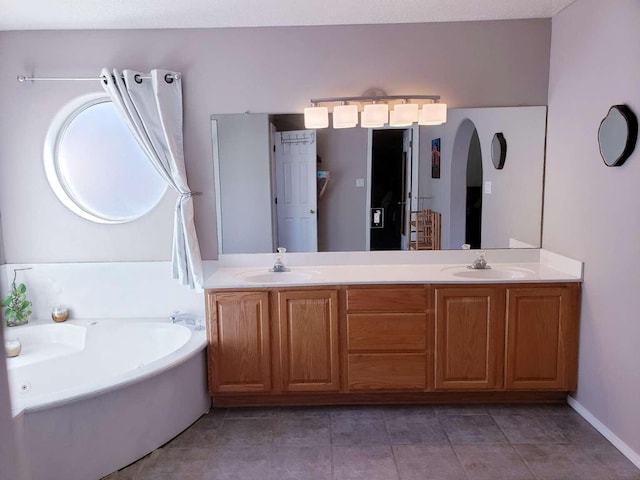 full bath featuring a bath, double vanity, a sink, and tile patterned floors