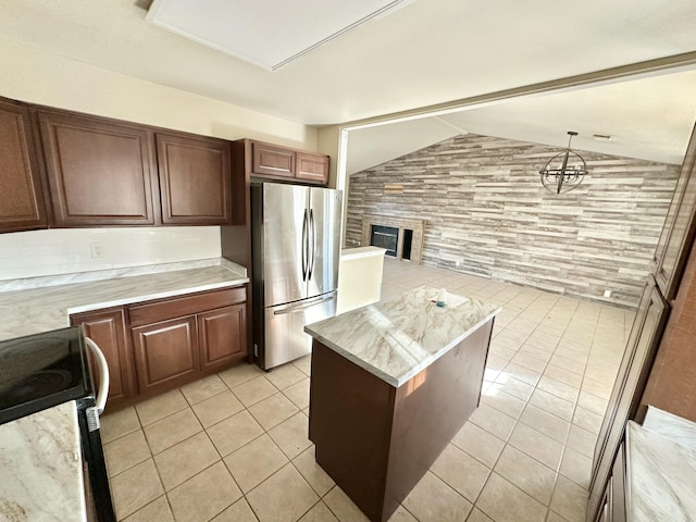 kitchen with a center island, range with electric stovetop, light tile patterned floors, hanging light fixtures, and freestanding refrigerator