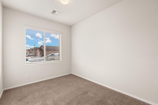 empty room featuring carpet, visible vents, and baseboards