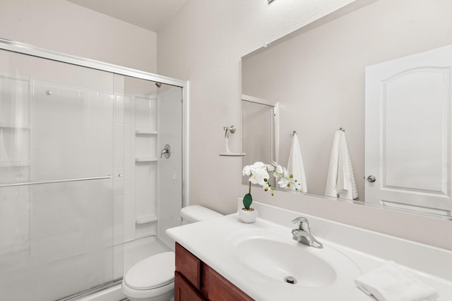 bathroom with a shower stall, vanity, and toilet