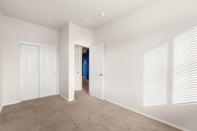 unfurnished bedroom featuring light carpet, a closet, and baseboards