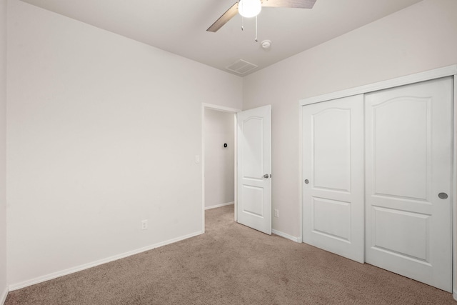 unfurnished bedroom with light carpet, a ceiling fan, baseboards, and a closet