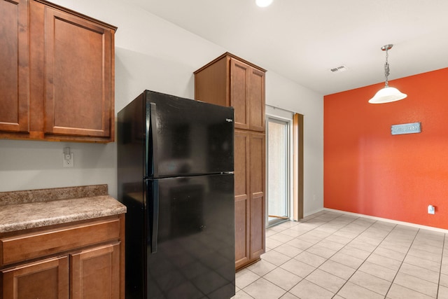 kitchen with brown cabinetry, visible vents, pendant lighting, and freestanding refrigerator