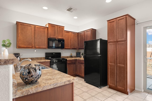 kitchen featuring visible vents, brown cabinetry, a sink, a peninsula, and black appliances