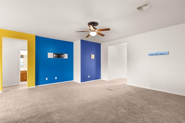 carpeted spare room featuring visible vents and a ceiling fan