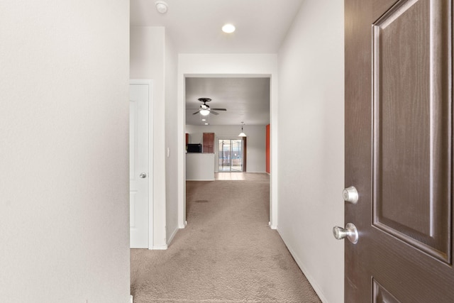 hallway featuring carpet flooring and baseboards