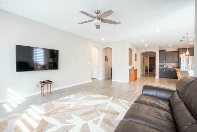 living room featuring arched walkways, recessed lighting, a ceiling fan, and light wood-style floors