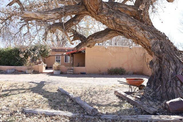 back of house featuring fence and stucco siding