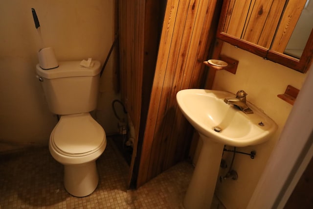 bathroom with toilet, a sink, and tile patterned floors