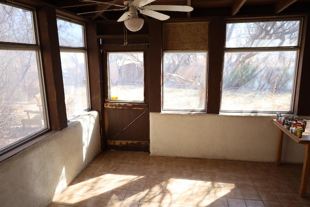 unfurnished sunroom featuring ceiling fan and a wealth of natural light