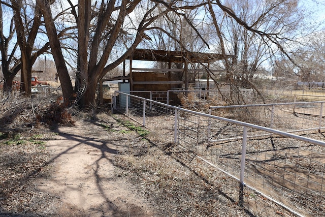 view of yard featuring a rural view, an exterior structure, an outdoor structure, and fence