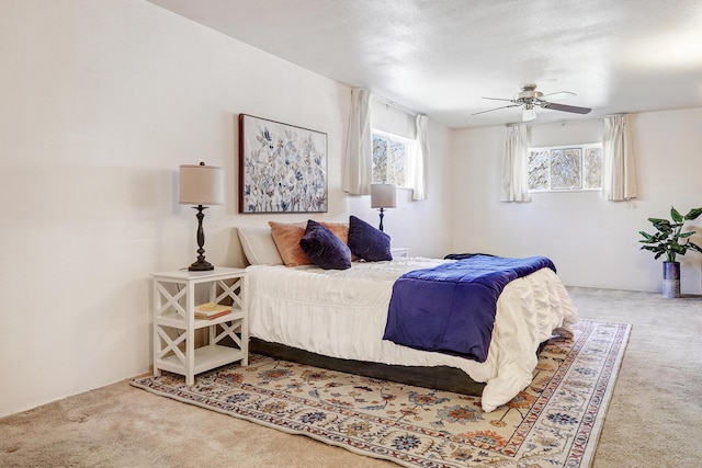 carpeted bedroom featuring ceiling fan and a textured ceiling