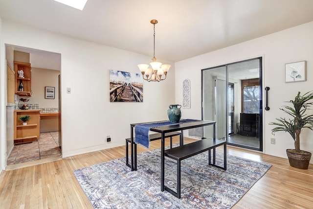 dining space featuring baseboards, a chandelier, and wood finished floors