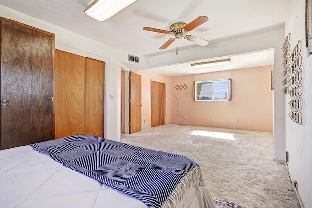 bedroom with carpet floors, visible vents, two closets, and a ceiling fan