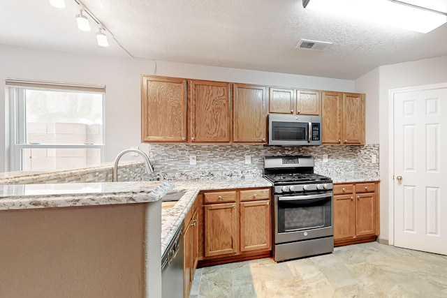 kitchen featuring visible vents, decorative backsplash, appliances with stainless steel finishes, a textured ceiling, and a sink