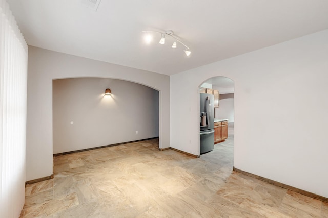 spare room with arched walkways, visible vents, and baseboards