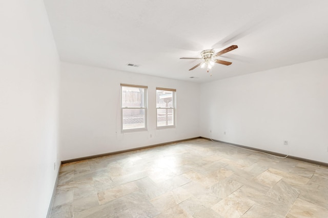 spare room featuring a ceiling fan, visible vents, and baseboards