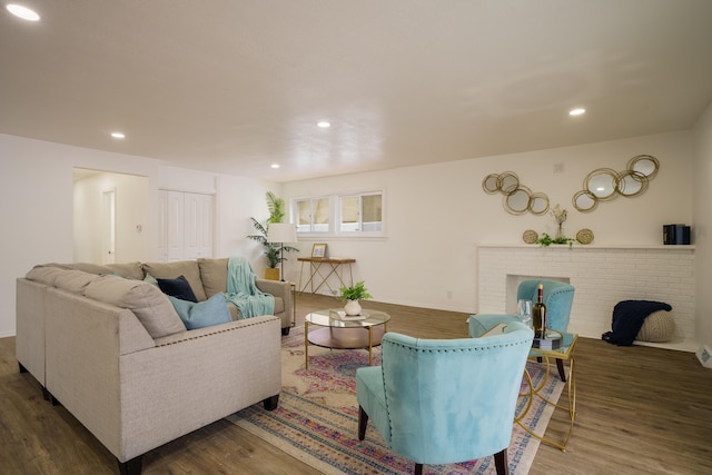 living area featuring a brick fireplace, recessed lighting, and wood finished floors