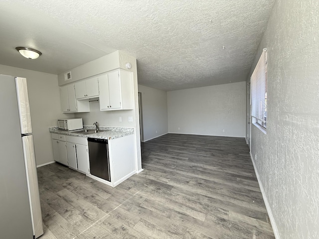 kitchen with light countertops, light wood-style flooring, freestanding refrigerator, white cabinetry, and dishwasher