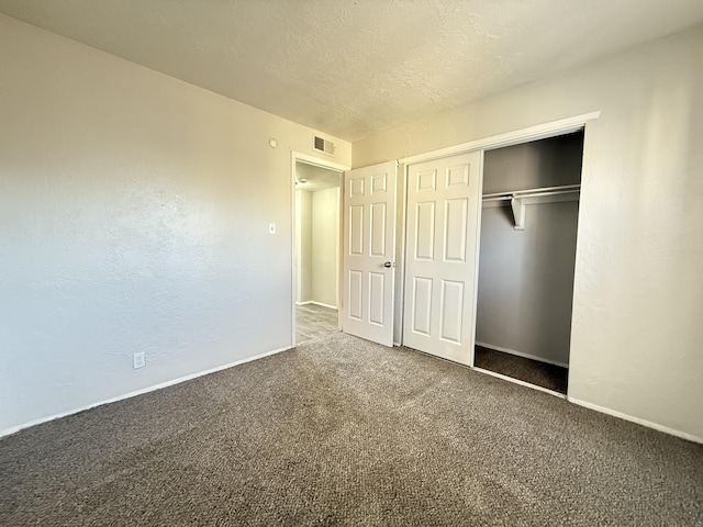 unfurnished bedroom with a textured ceiling, a textured wall, visible vents, a closet, and carpet