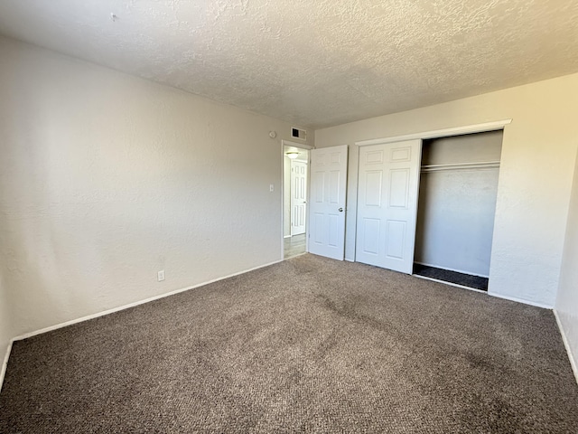 unfurnished bedroom featuring visible vents, a textured wall, a textured ceiling, carpet floors, and a closet