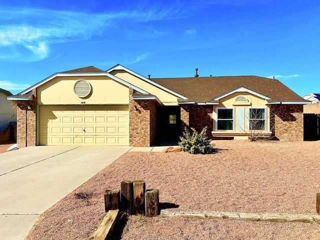 ranch-style home featuring an attached garage, a shingled roof, concrete driveway, and brick siding