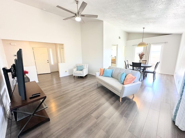 living room featuring high vaulted ceiling, ceiling fan, a textured ceiling, and wood finished floors