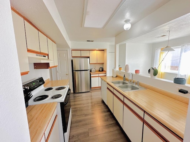 kitchen with electric range oven, light countertops, freestanding refrigerator, and under cabinet range hood