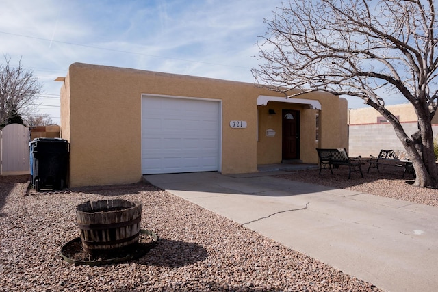 pueblo revival-style home featuring driveway, a garage, and stucco siding