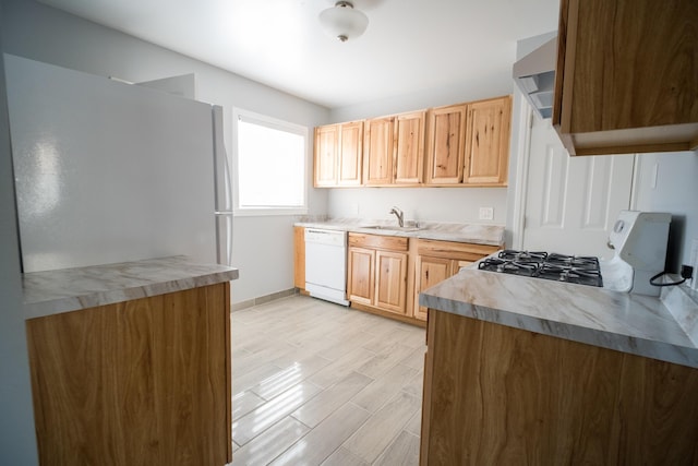 kitchen featuring light wood finished floors, light countertops, light brown cabinets, a sink, and white appliances