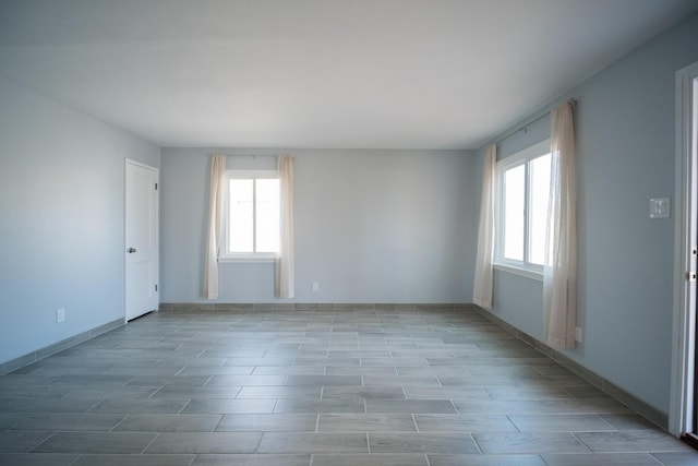 spare room featuring baseboards, light wood-type flooring, and a healthy amount of sunlight