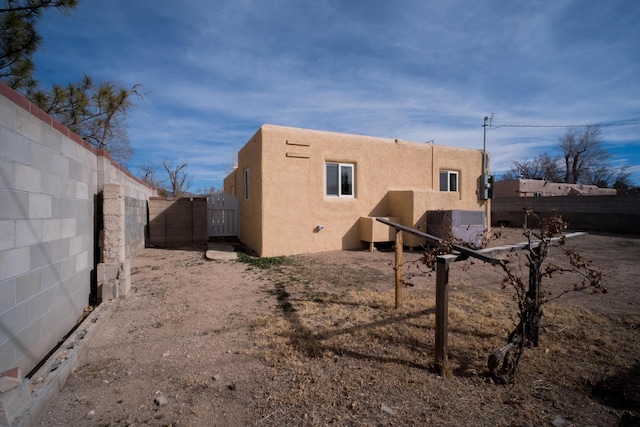 back of property featuring fence, a gate, and stucco siding