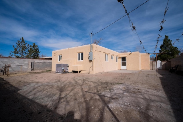 back of house with a gate, fence, and stucco siding