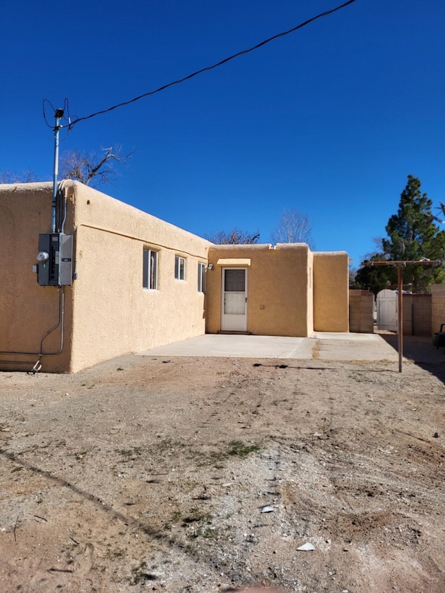 rear view of house featuring a gate, a patio area, fence, and stucco siding