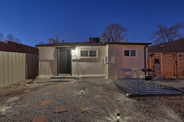 back of house at twilight with cooling unit, a fenced backyard, and stucco siding