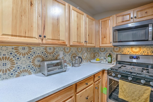 kitchen featuring a toaster, decorative backsplash, light brown cabinetry, appliances with stainless steel finishes, and light stone countertops