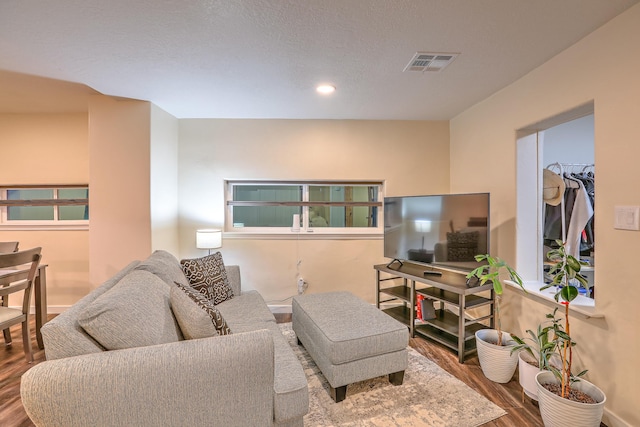 living area with a textured ceiling, visible vents, and wood finished floors