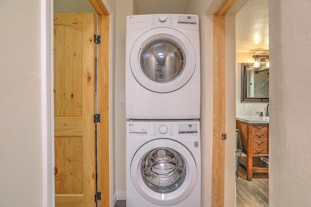 clothes washing area with laundry area, wood finished floors, and stacked washer and clothes dryer