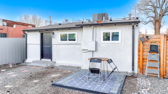 rear view of property with cooling unit, fence, and stucco siding