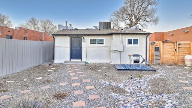 rear view of property with central air condition unit, fence, a gate, and stucco siding