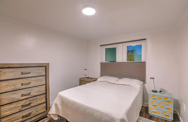 bedroom with dark wood-style floors, crown molding, and baseboards