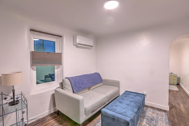 living area featuring arched walkways, a wall mounted AC, dark wood finished floors, and baseboards