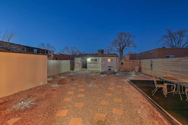 yard at dusk featuring a fenced backyard and central air condition unit