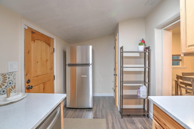 kitchen with light stone counters, dark wood finished floors, freestanding refrigerator, a textured ceiling, and baseboards