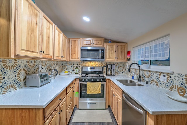 kitchen with light stone counters, tasteful backsplash, lofted ceiling, appliances with stainless steel finishes, and a sink