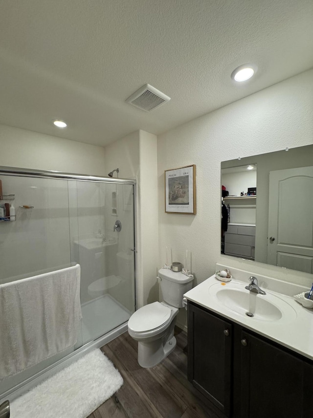 full bathroom featuring visible vents, toilet, a stall shower, vanity, and wood finished floors