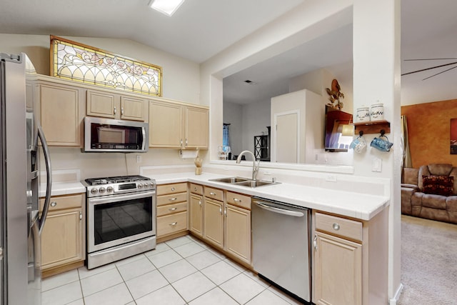 kitchen with vaulted ceiling, stainless steel appliances, light countertops, light brown cabinets, and a sink