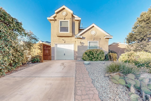 traditional-style house featuring concrete driveway, fence, an attached garage, and stucco siding