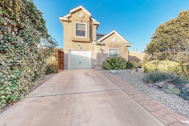 traditional-style home with a garage, concrete driveway, fence, and stucco siding